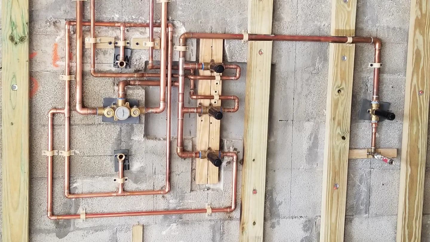 Copper shower manifold and valves on a concrete-block wall
