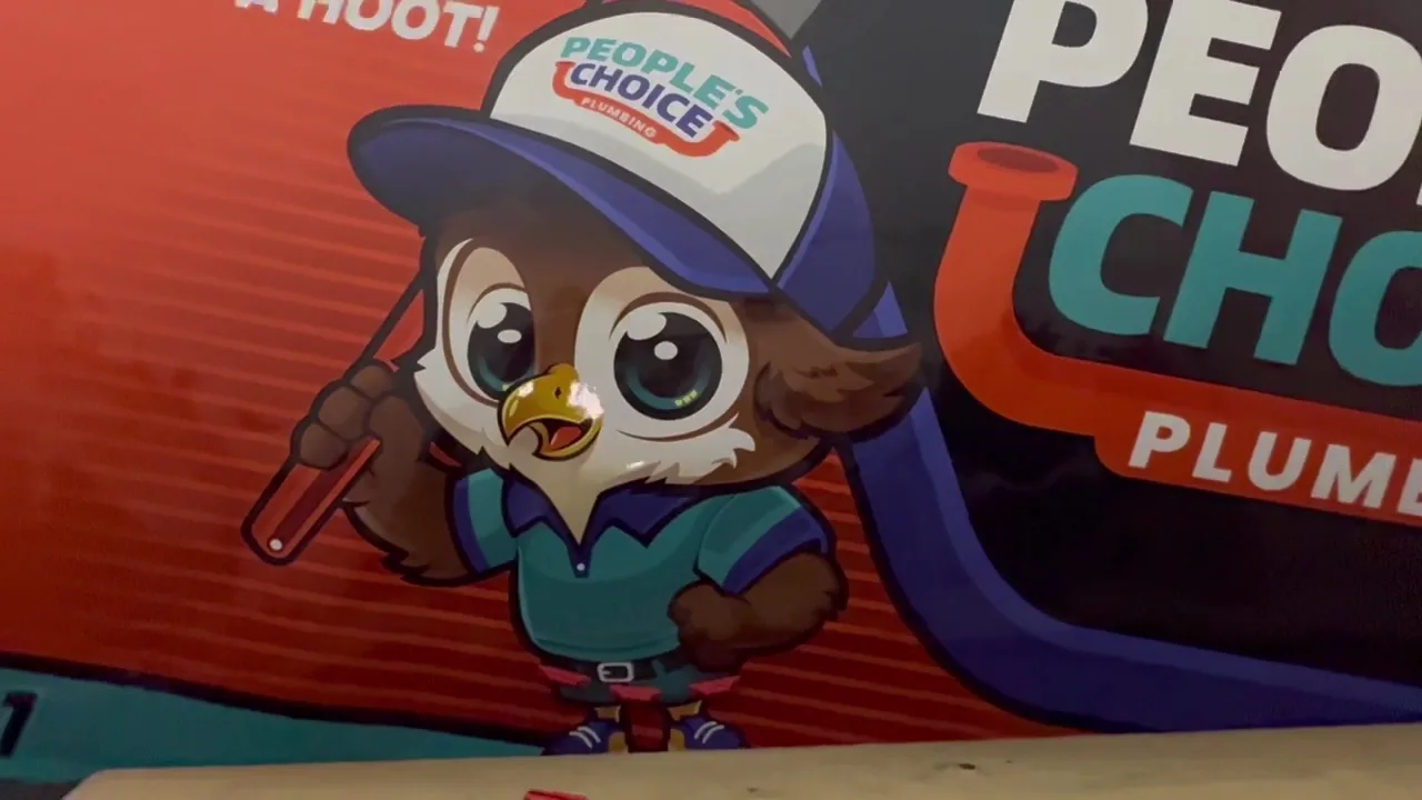 People's Choice Plumbing owl mascot in uniform holding a wrench
