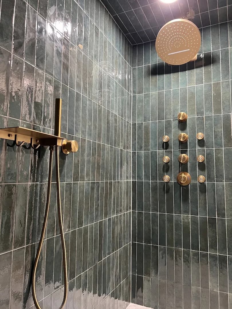 Teal-tile walk-in shower with brushed-gold rain head and body jets